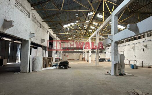A well-lit industrial shed in the Taloja MIDC with large roller shutter doors and a spacious interior.