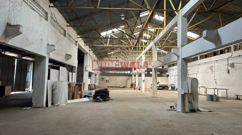 A well-lit industrial shed in the Taloja MIDC with large roller shutter doors and a spacious interior.
