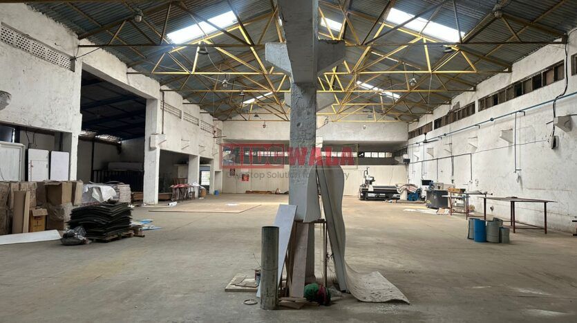 A well-lit industrial shed in the Taloja MIDC with large roller shutter doors and a spacious interior.