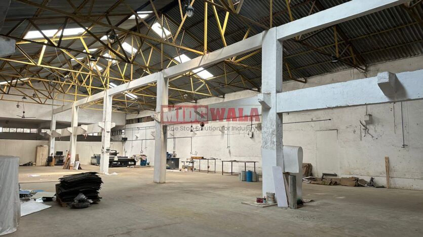 A well-lit industrial shed in the Taloja MIDC with large roller shutter doors and a spacious interior.