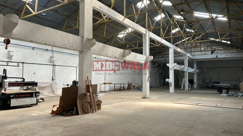 A well-lit industrial shed in the Taloja MIDC with large roller shutter doors and a spacious interior.