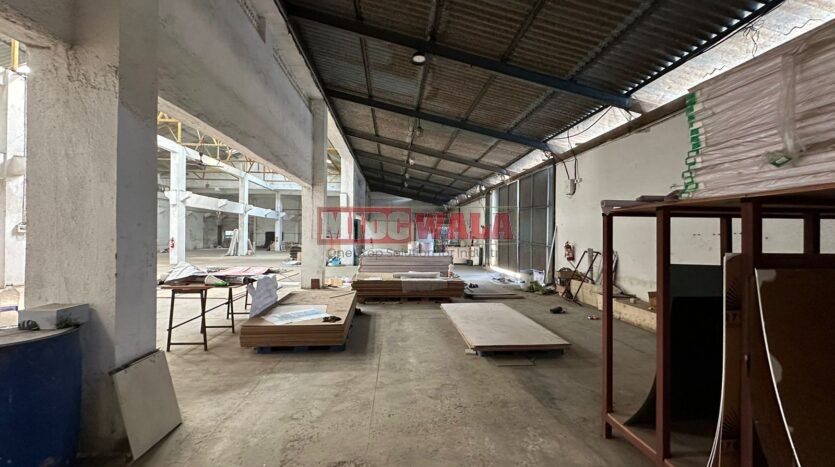 A well-lit industrial shed in the Taloja MIDC with large roller shutter doors and a spacious interior.