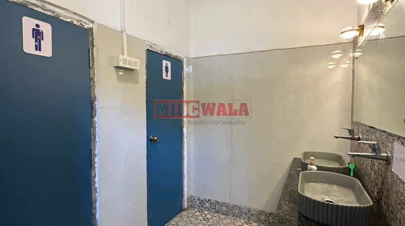 A well-lit industrial shed in the Taloja MIDC with large roller shutter doors and a spacious interior.