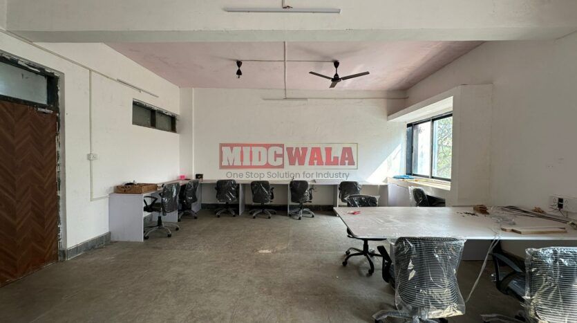 A well-lit industrial shed in the Taloja MIDC with large roller shutter doors and a spacious interior.