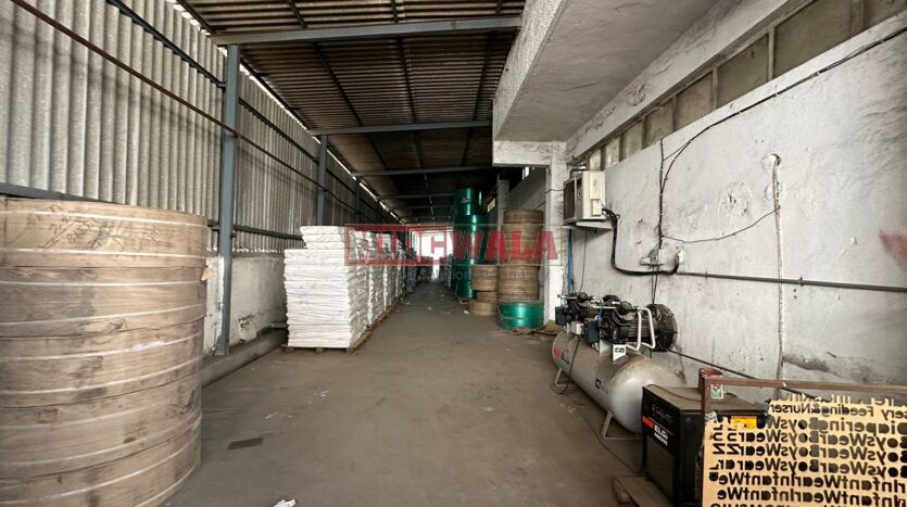 A well-lit industrial shed in the Taloja MIDC with large roller shutter doors and a spacious interior.