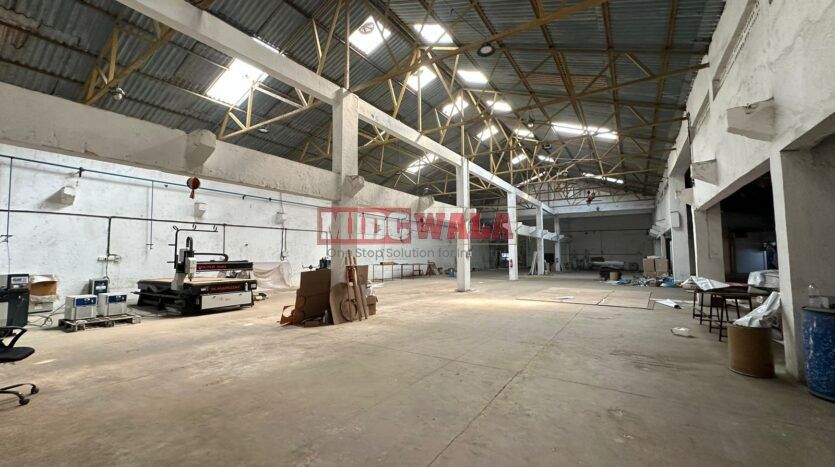 A well-lit industrial shed in the Taloja MIDC with large roller shutter doors and a spacious interior.